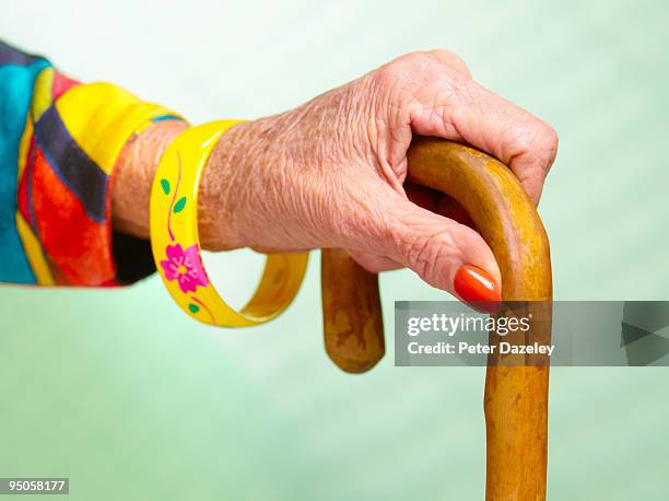70 year old woman's hand holding walking stick - hand holding stick stock pictures, royalty-free photos & images