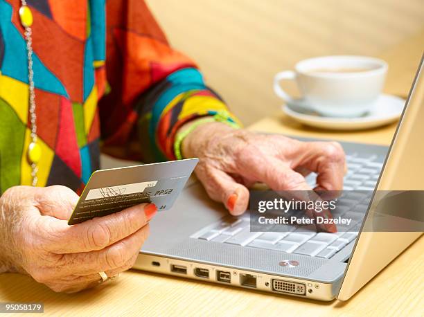 70 year old woman buying on line - spending money stock pictures, royalty-free photos & images