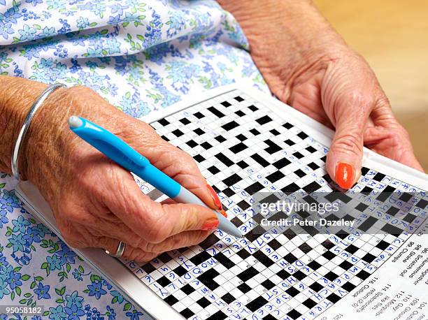 70 year old woman doing crossword puzzle - korsord bildbanksfoton och bilder