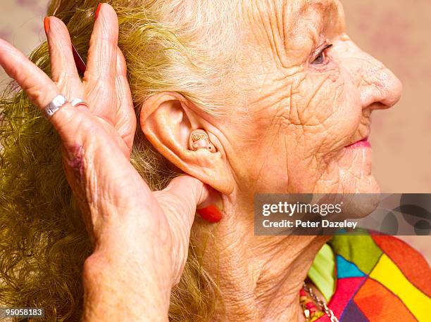 70 year old woman with hearing aid - hearing aids stock pictures, royalty-free photos & images