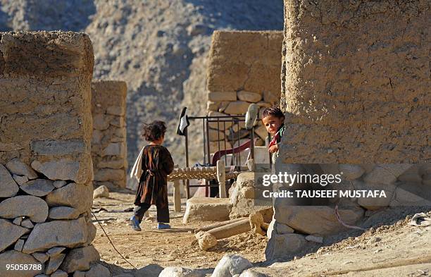 Afghan children watch US soldiers from 2-77 Field Artillery Steel Warriors on patrol in the mountains of Nuristan Province on December 23, 2009. US...