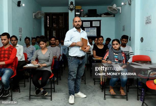 Surbir Singh an Indian shorthand teacher, poses for a picture at a stenography centre surrounded by students in Faridabad on April 24, 2018. - Ahead...