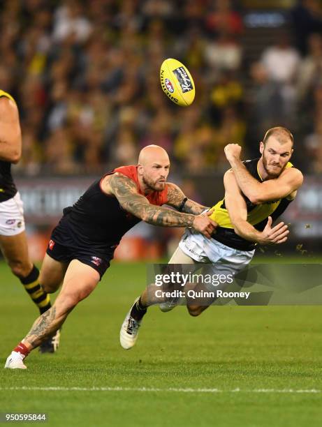 Kamdyn McIntosh of the Tigers handballs whilst being tackled by Nathan Jones of the Demons during the round five AFL match between the Melbourne...