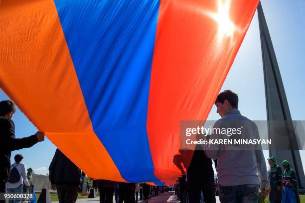 People carrying a giant Armenian flag take part in a ceremony commemorating the 103rd anniversary of the massacre of 1.5 million of Armenians by...