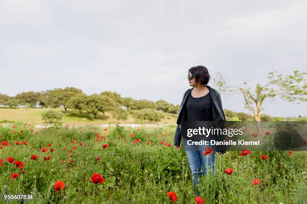 young woman  standing in field of red poppies, selective focus - stehmohn stock-fotos und bilder