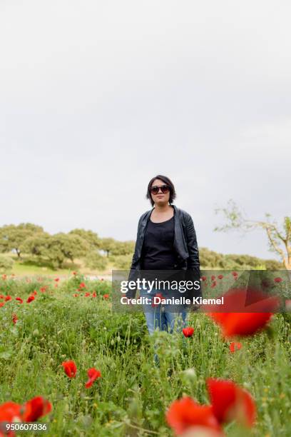 young woman  standing in field of red poppies, selective focus - stehmohn stock-fotos und bilder