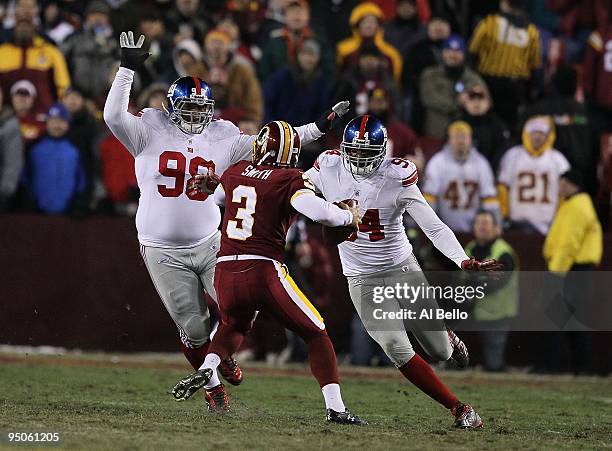 Hunter Smith of the Washington Redskins is tackled by Mathias Kiwanuka and Fred Robbins of the New York Giants on a fake field goal during their game...