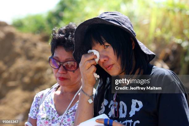 Filipino journalist wipes tears away as others offer flowers, prayers and light candles at the site where 57 people, including many journalists, were...