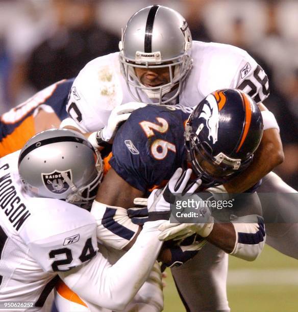 Denver Broncos Clinton Portis gets 15 yards before being tackled by Oakland Raiders Charles Woodson and Rod Woodson in the first half, 11 November...