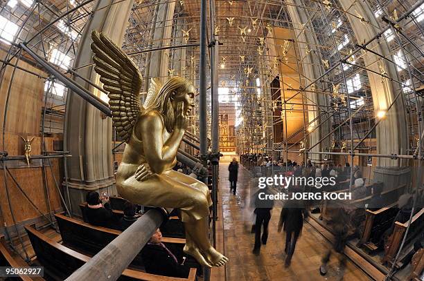 Church visitors walk past one of 300 golden angels attached to scaffolding in the Holy Cross church in the southern German city of Munich on December...