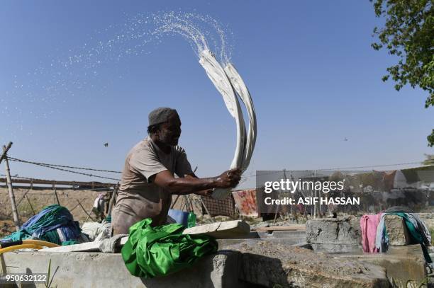 In this photograph taken on April 23 a Pakistani dhobi or laundry man, beats clothes on a stone at a traditional Dhobi Ghat or open-air laundry...