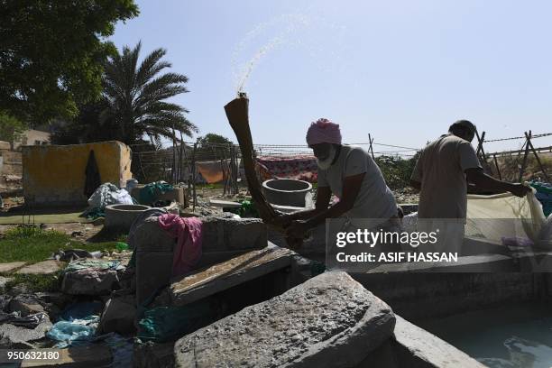 In this photograph taken on April 23 a Pakistani dhobi or laundry man, beats clothes on a stone at a traditional Dhobi Ghat or open-air laundry...