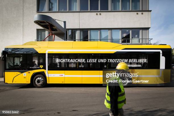 Man with helmet walks in front of a charging electric bus on April 24, 2018 in Berlin, Deutschland.