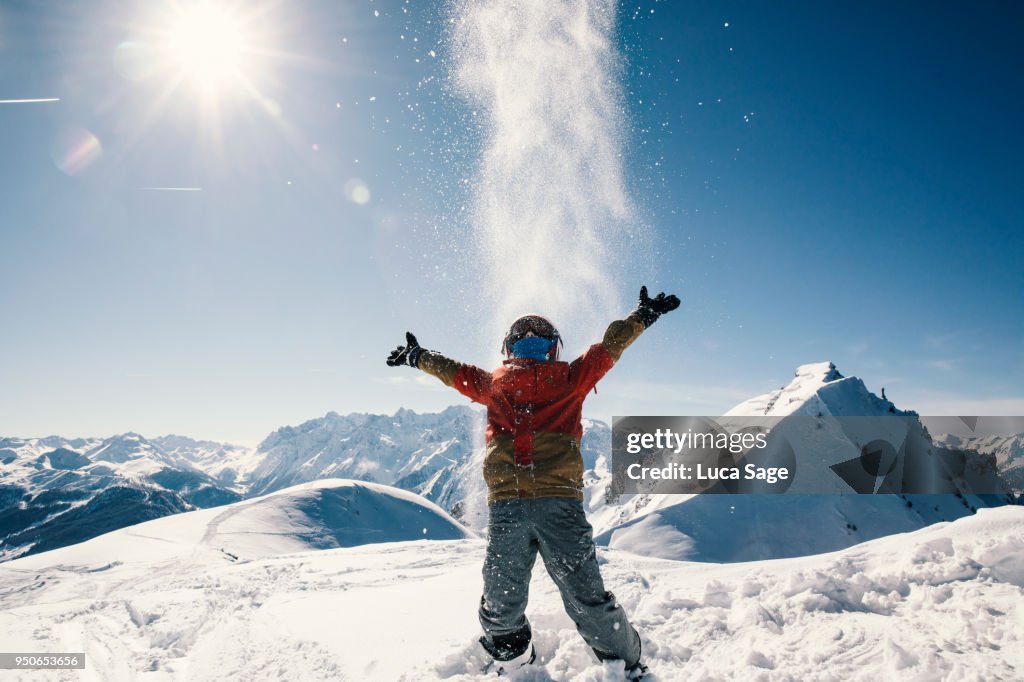 Young boy enjoying sun and snow fun on top of a mountain