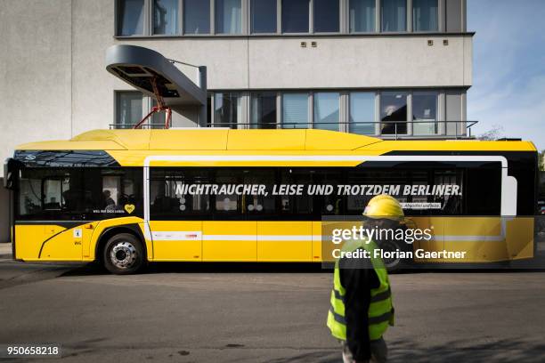 Man with helmet walks in front of a charging electric bus on April 24, 2018 in Berlin, Germany.