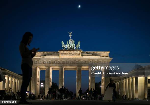 Woman stands with her smartphone in front of the Brandenburg Gate on April 19, 2018 in Berlin, Germany.