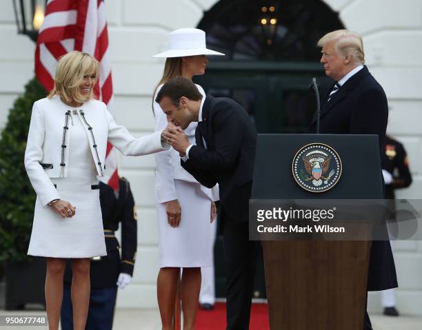 French President Emmanuel Macron kisses the hand of his wife, French first lady Brigitte Macron, as they are welcomed by U.S President Donald Trump...