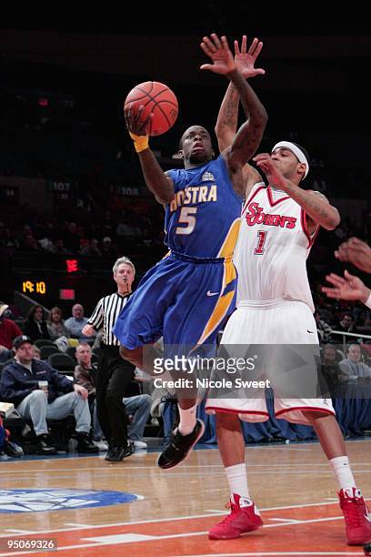 Chaz Williams of Hofstra Pride goes up for a shot against D.J. Kennedy of St. John's Red Storm at Madison Square Garden on December 20, 2009 in New...