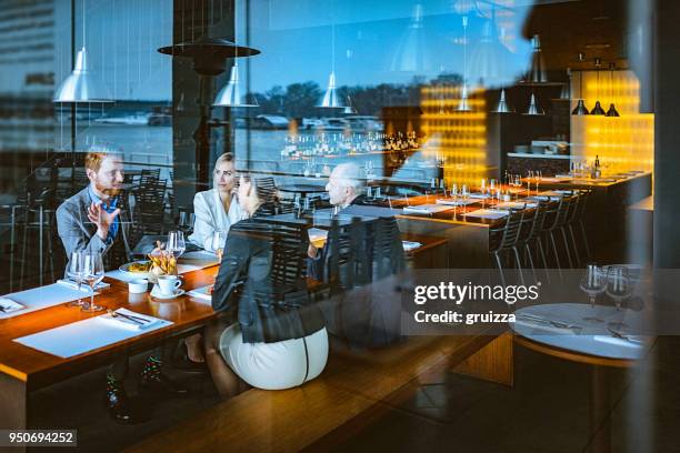 group of friends enjoy chatting during lunch time in a high-end restaurant - view-through-restaurant-window stock pictures, royalty-free photos & images