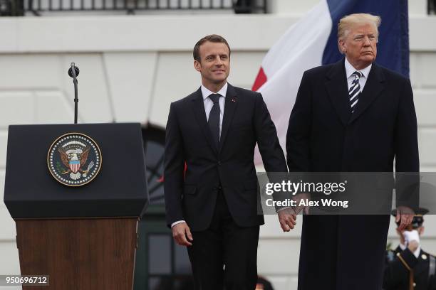 President Donald Trump and French President Emmanuel Macron hold hands during a state arrival ceremony at the South Lawn of the White House April 24,...