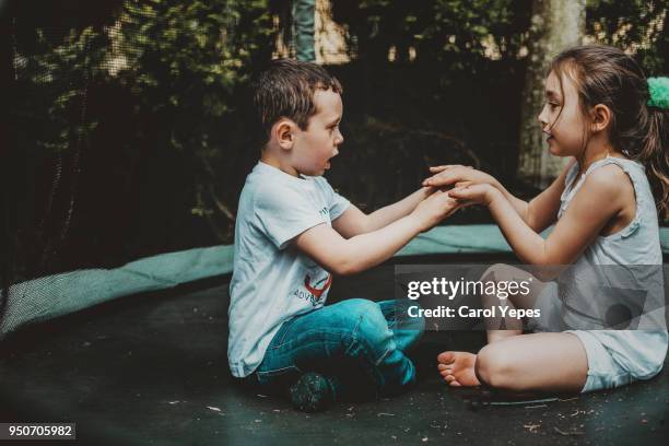 two kids playing clapping hands game outdoors in back yard - clapping game stock pictures, royalty-free photos & images