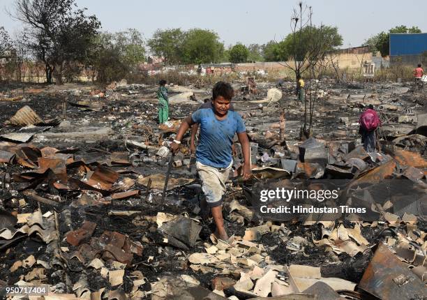 Residents rummage through debris after their houses were gutted in a fire at a slum in Shahbad Dairy near Rohini, on April 24, 2018 in New Delhi,...