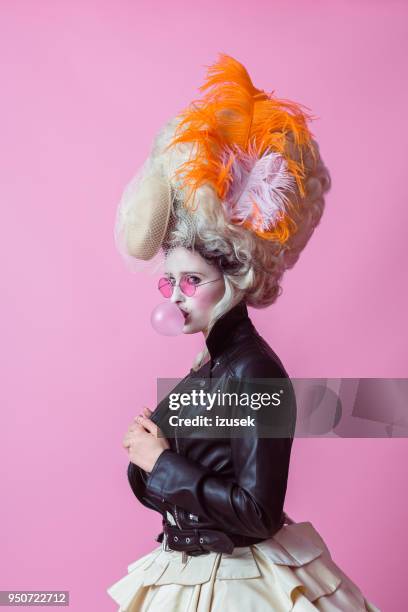 portrait of rebel woman wearing baroque wig and leather jacket, pink backgroud - wig costumes stock pictures, royalty-free photos & images