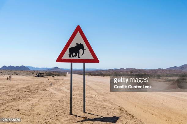 elephant warning sign on dirt road, damaraland, namibia - desert elephant stock pictures, royalty-free photos & images