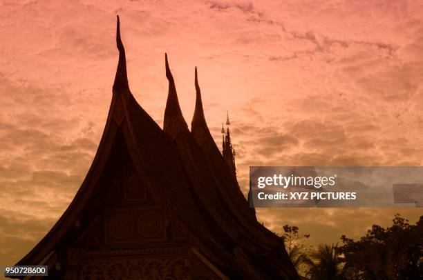 wat xieng thong, temple silouetted against the setting sun, luang prabang, laos - wat xieng thong stock pictures, royalty-free photos & images