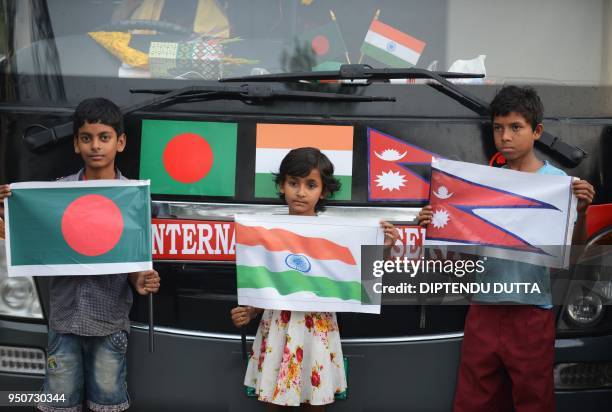 Indian children hold the national flags of Bangladesh, Indian and Nepal to welcome the trial Dhaka-Kathmandu bus service at the main entrance of the...