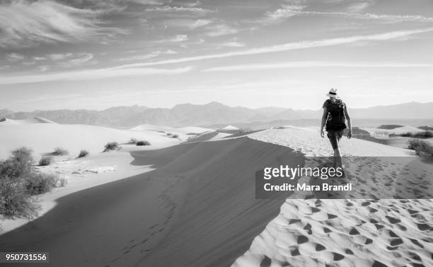 young man hiking on sand dunes, tourist, mesquite flat sand dunes, foothills of amargosa range behind, death valley, death valley national park, california, usa - howse peak stock-fotos und bilder