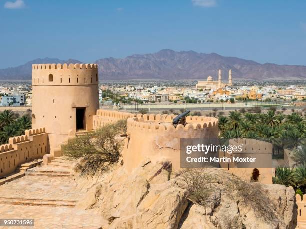 nakhal fort or husn al heem, fortress above nakhl oasis on jebel nakhl massif, historical loam construction, town of nakhal and great mosque behind, al batinah, oman - loam stock pictures, royalty-free photos & images