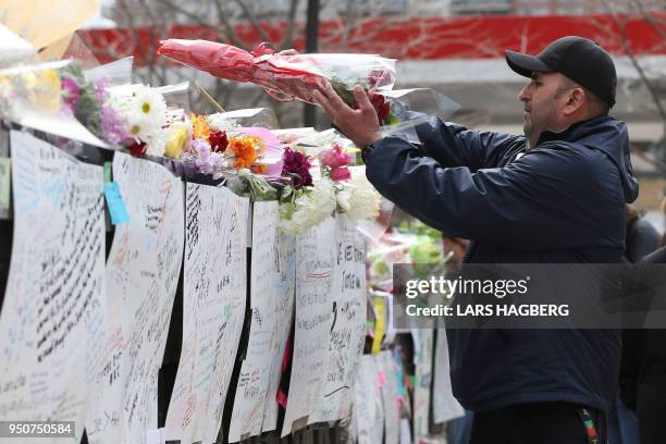 Man leaves flowers on April 24 at a makeshift memorial for victims in the van attack in Toronto, Ontario. - A van driver who ran over 10 people when...