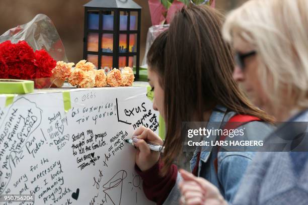 Woman writes a note on April 24, 2018 at a makeshift memorial for victims in the van attack in Toronto, Ontario. - A van driver who ran over 10...