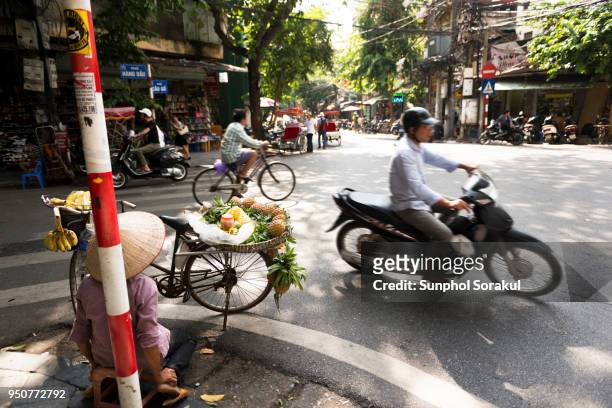 woman selling pineapple at street intersection in hanoi old quarter - sunphol foto e immagini stock