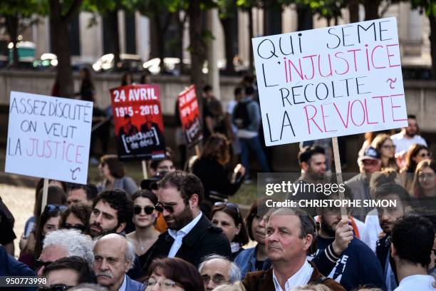 Man holds up a sign that reads in French, 'Enough discussion we want justice' and 'He who sows injustice reaps a revolt' , as Armenians gather to...