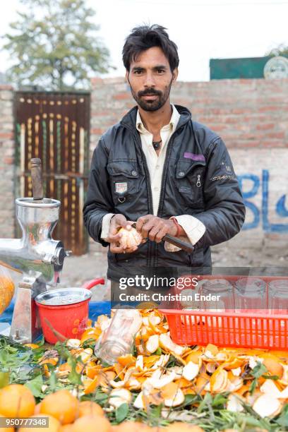 Street vendor is peeling an orange with a knife to make orange juice later on at a marketplace on February 27, 2014 in Lahore, Pakistan. Lahore is...