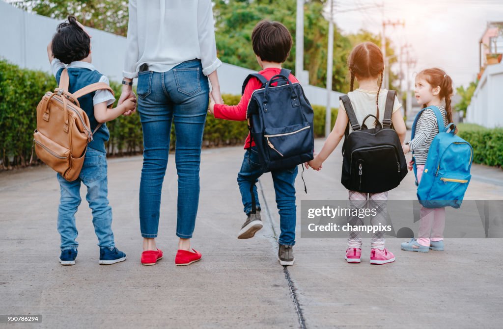 Mother and pupil and kids holding hands going to school in first class with schoolbag or satchel walking to school bus, Parent and son,sister preschool