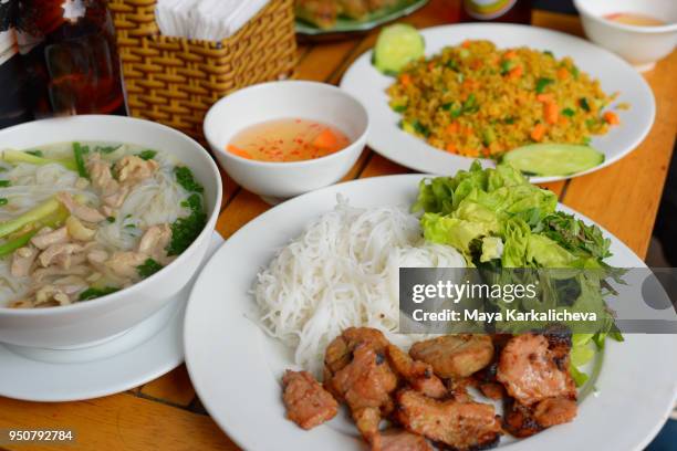 variety of vietnamese food, grilled pork with salad, mint and rice noodle soup with beef, pho bo - nuoc cham stock-fotos und bilder