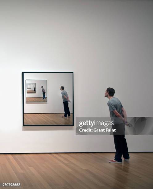 young man looking at himself in framed photograph - museum stockfoto's en -beelden