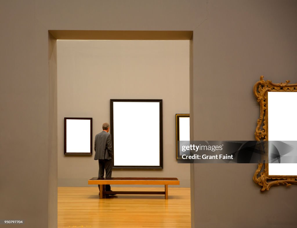 Man in art gallery looking at paintings