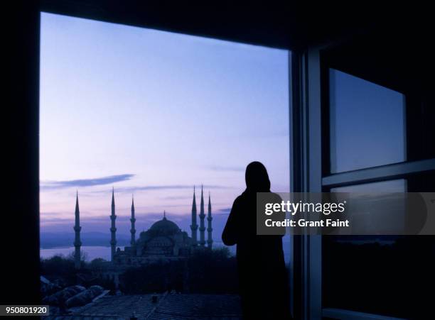 woman viewing blue mosque out window. - islam foto e immagini stock
