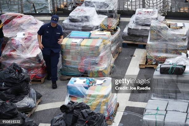 Crew member of the Coast Guard ship Legare walks among wrapped packages of approximately 12 tons of cocaine and 1 ton of marijuana before offloading...