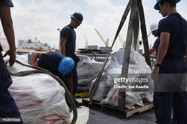 The crew of the Coast Guard ship Legare use a crane to offload wrapped packages of approximately 12 tons of cocaine and 1 ton of marijuana at Port...