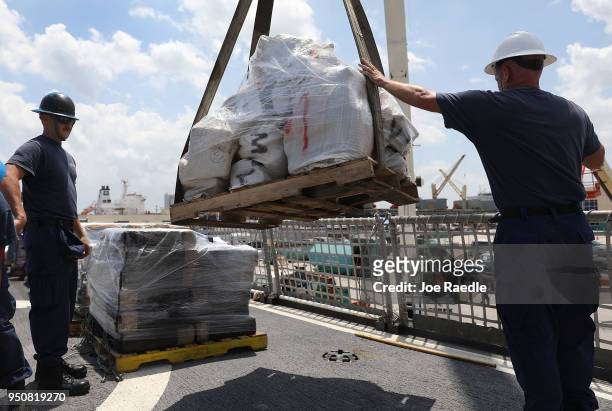The crew of the Coast Guard ship Legare use a crane to offload wrapped packages of approximately 12 tons of cocaine and 1 ton of marijuana at Port...
