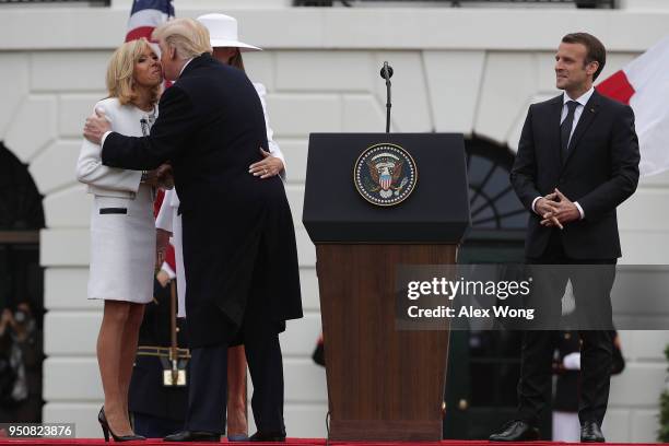 President Donald Trump kisses French first lady Brigitte Macron as French President Emmanuel Macron looks on during a state arrival ceremony at the...