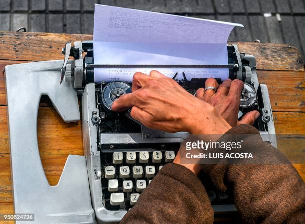 Street clerk Candelaria Pinilla types a letter on her typewriter, in front of the district taxing office in Bogota, on April 9, 2018. - Street clerks...