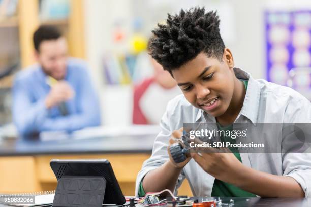 teenage boy builds robot in class - public school building stock pictures, royalty-free photos & images