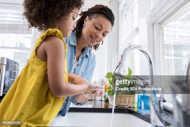 mom helps daughter wash hands - kitchen sink running water stock pictures, royalty-free photos & images