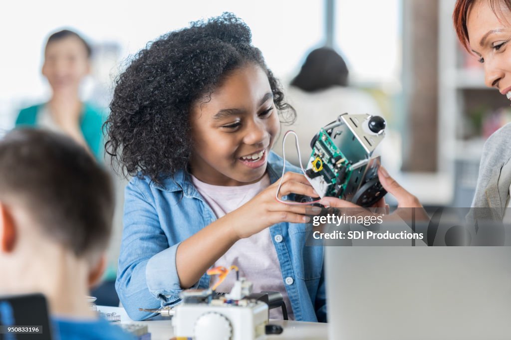 Souriant écolière crée le robot dans la classe de technologie